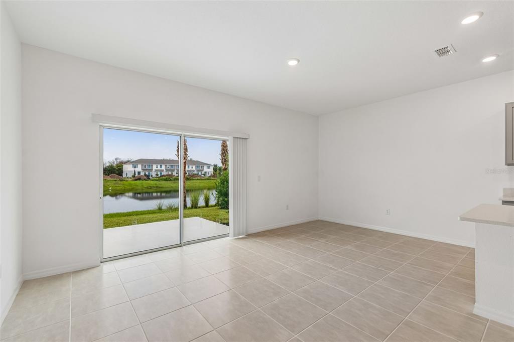 An empty room with light tile flooring, white walls, and a sliding glass door to water — 13159 STABLE PLACE, PARRISH, FL