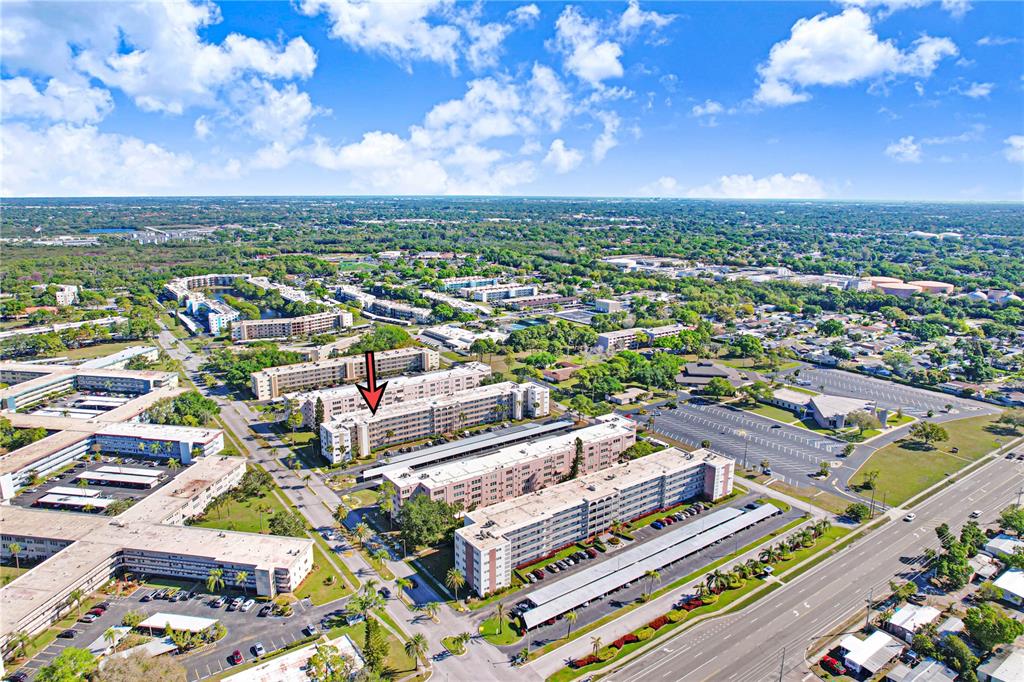 An aerial view shows multiple apartment buildings with parking lots and surrounding greenery — 5603 80TH STREET N UNIT 303, ST PETERSBURG, FL