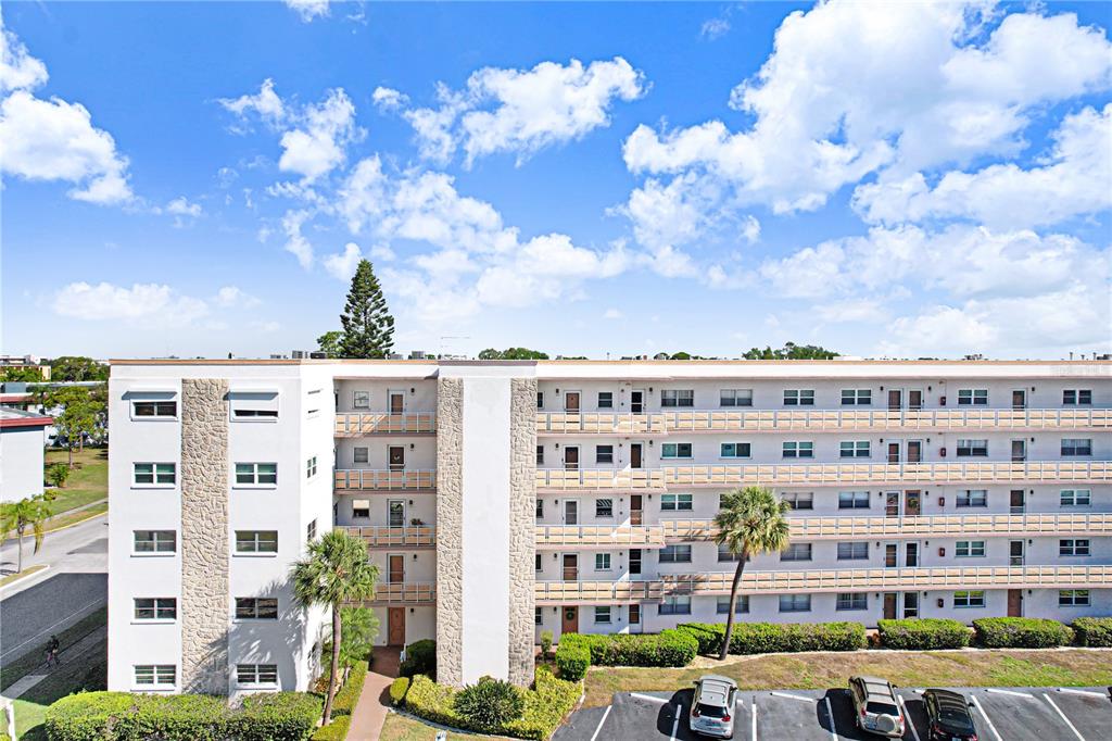 An exterior view of a multi-story apartment building with a parking lot in front — 5603 80TH STREET N UNIT 303, ST PETERSBURG, FL