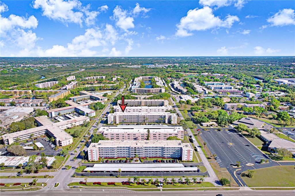 An aerial view shows a multi-story residential apartment complex surrounded by parking lots and greenery — 5603 80TH STREET N UNIT 303, ST PETERSBURG, FL