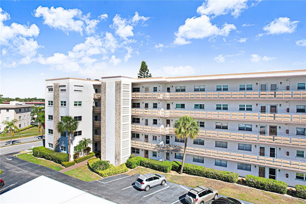 An exterior view of a multi-story apartment building with balconies and a parking lot — 5603 80TH STREET N UNIT 303, ST PETERSBURG, FL