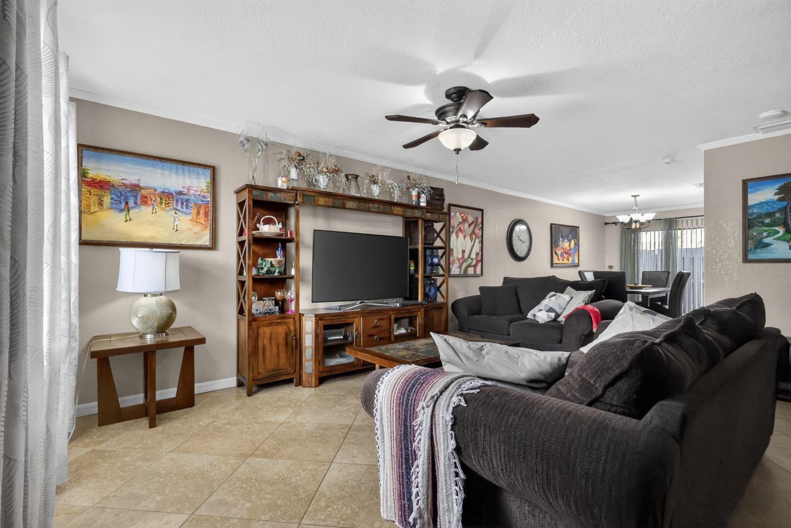 A living room features tile flooring, a wooden entertainment center, and dark upholstered furniture — 104 Shoreview Drive # 104, FL 33463, FL