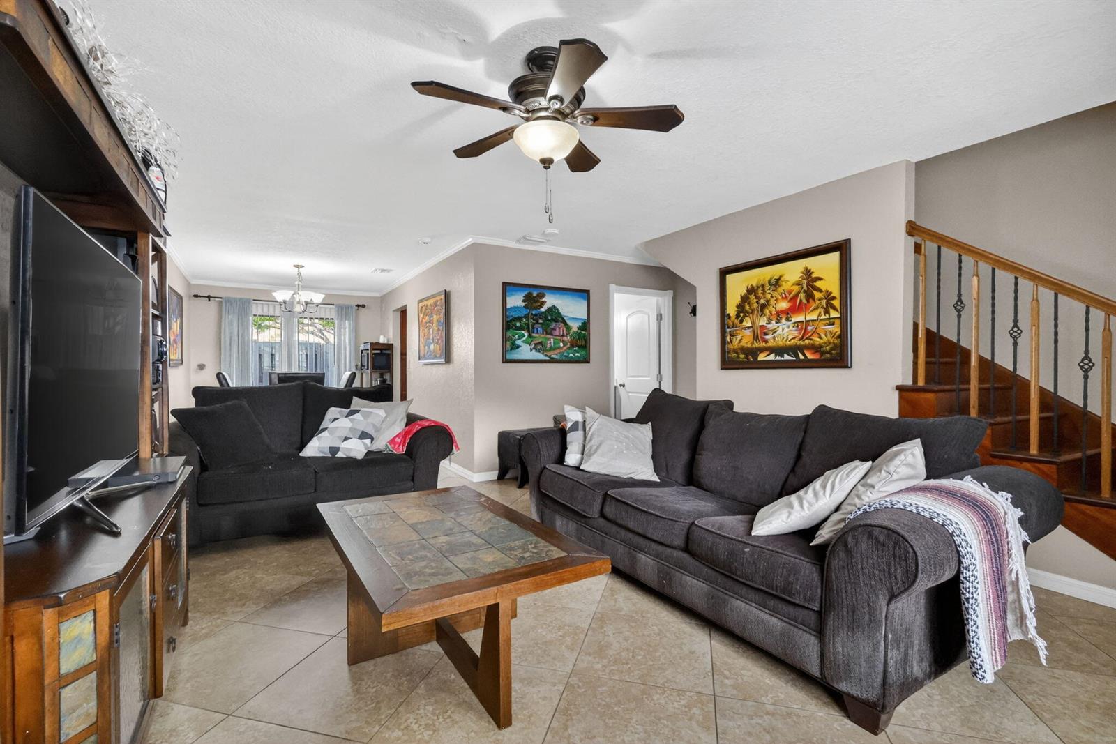A living room features dark sofas, a tile-topped coffee table, and a staircase with railings — 104 Shoreview Drive # 104, FL 33463, FL