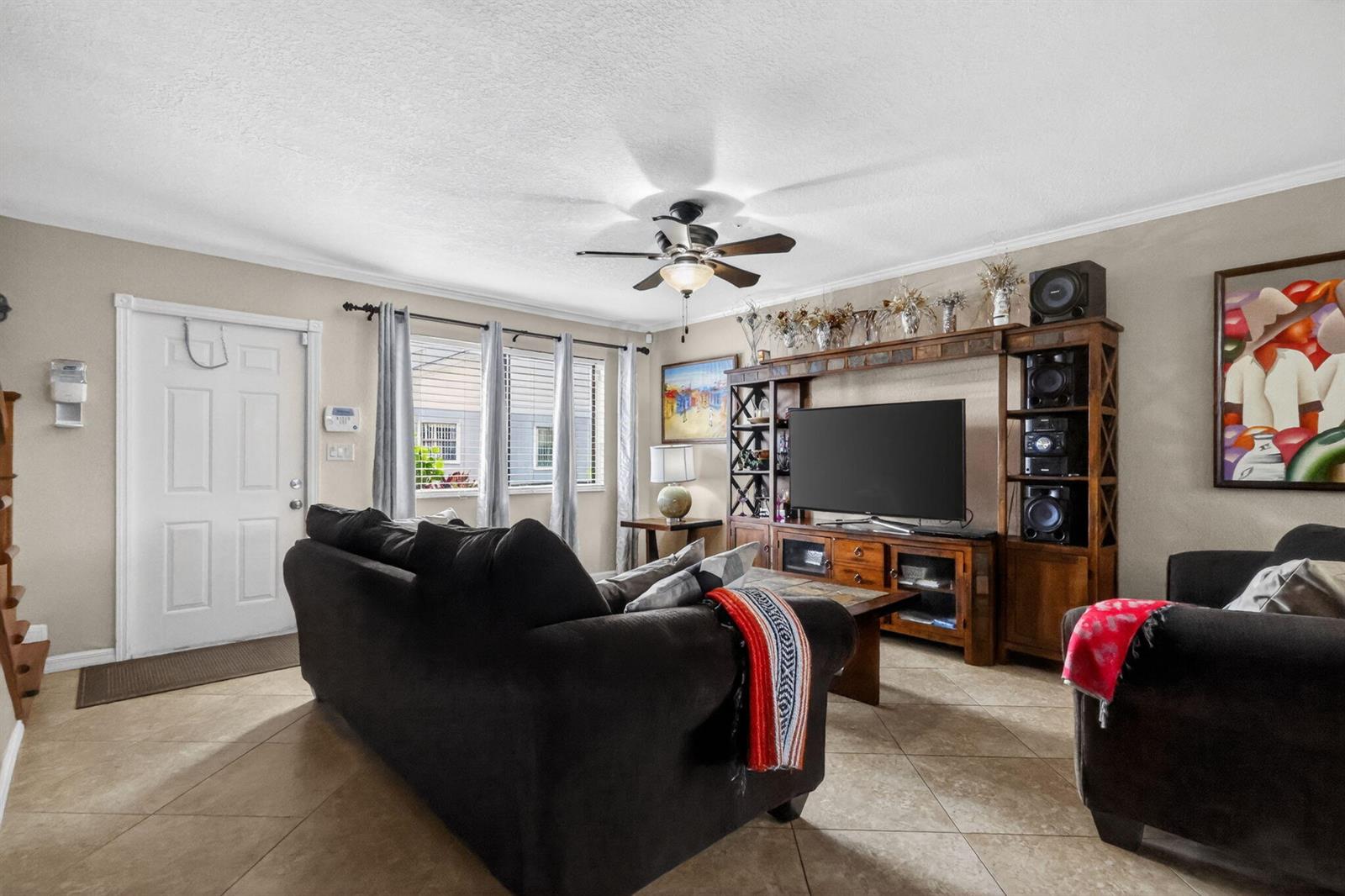 A living room features a dark sofa, a large wooden entertainment center, and tile flooring — 104 Shoreview Drive # 104, FL 33463, FL
