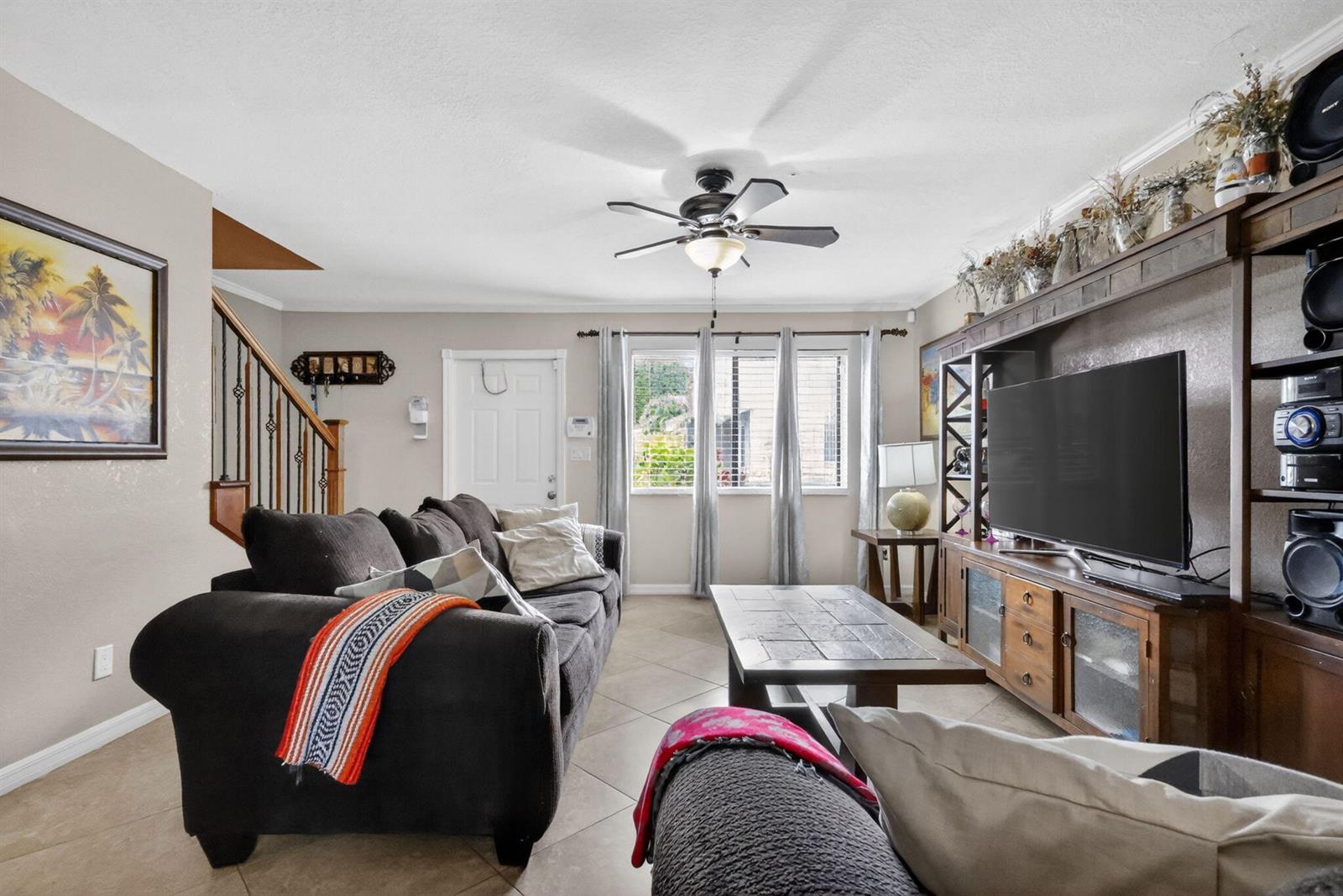 A living room features a dark sofa, a tile-topped coffee table, and a large entertainment center — 104 Shoreview Drive # 104, FL 33463, FL