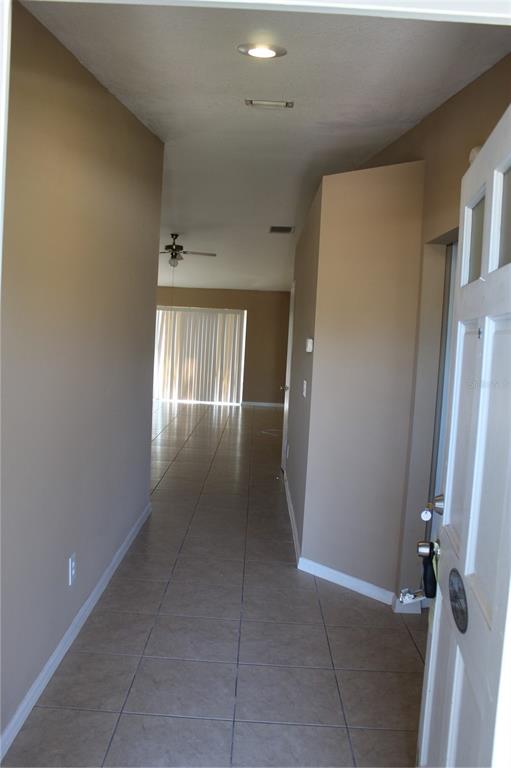 A tiled entryway leads into an open living area with a ceiling fan and blinds — 11111 BRAMBLEBRUSH STREET, TAMPA, FL