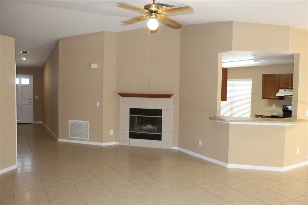 A living room with tile flooring, a fireplace, and an opening to the kitchen — 11111 BRAMBLEBRUSH STREET, TAMPA, FL