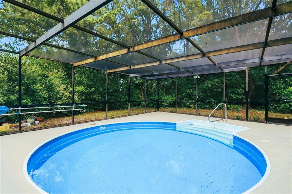 A round above-ground swimming pool is enclosed within a screened-in patio area — 5 SYCAMORE COURT N, HOMOSASSA, FL
