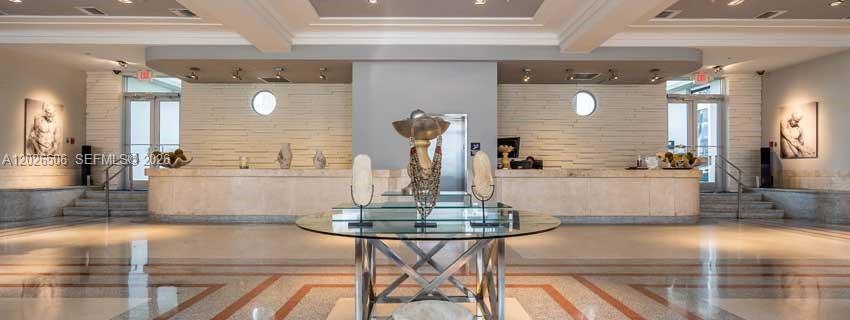A hotel lobby features a central glass table, a long stone reception desk, and artwork — 435 21st St # 212, Miami Beach FL 33139, MIAMI BEACH, FL