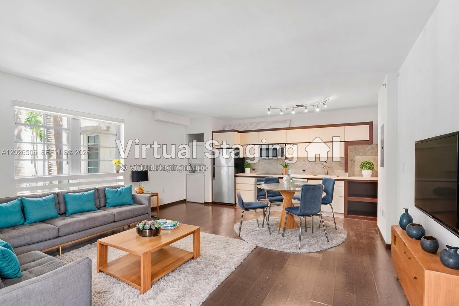This open-concept living and dining area features wood flooring, a modern kitchen, and virtual staging — 435 21st St # 212, Miami Beach FL 33139, MIAMI BEACH, FL
