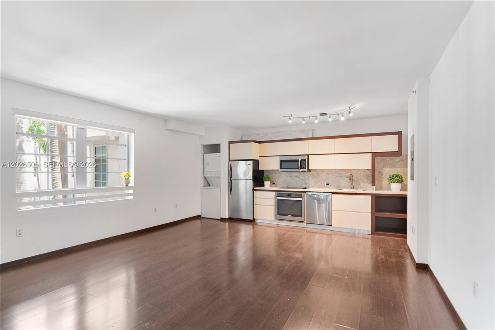 An open-concept kitchen and living area features dark wood floors and stainless steel appliances — 435 21st St # 212, Miami Beach FL 33139, MIAMI BEACH, FL
