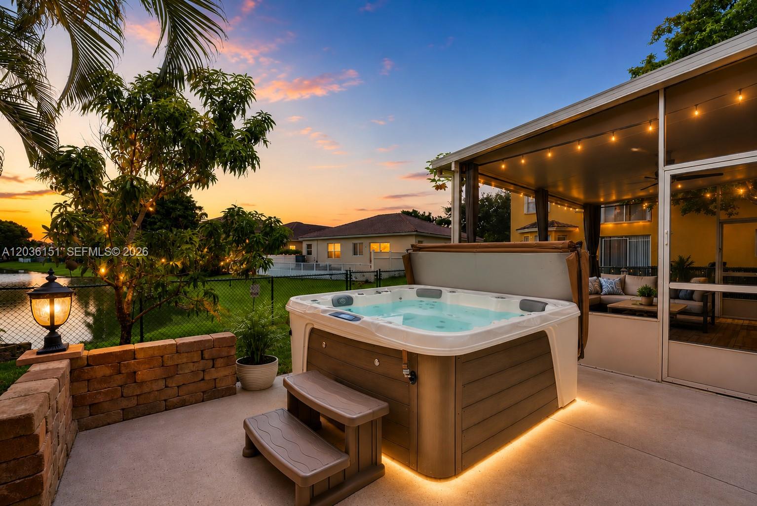 A hot tub sits on a concrete patio next to a screened-in porch at sunset — 1611 SE 16th St, Homestead FL 33035, HOMESTEAD, FL
