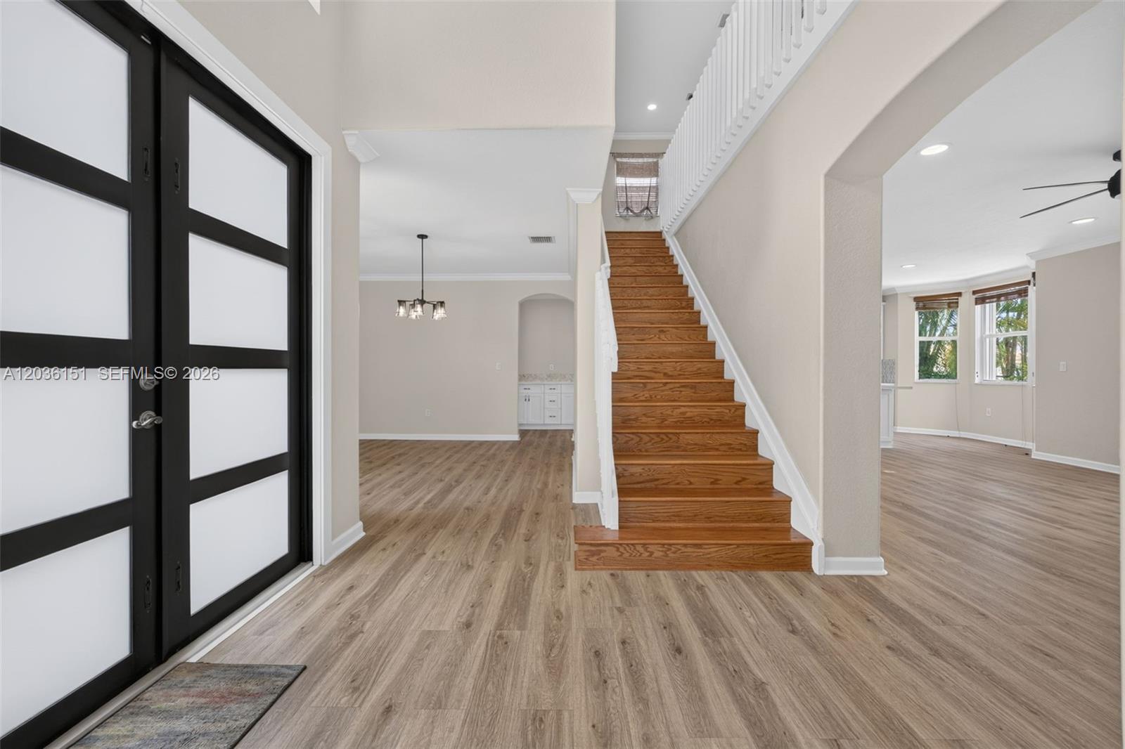 An entryway features wood-look flooring, a wooden staircase, and a modern black-framed glass door — 1611 SE 16th St, Homestead FL 33035, HOMESTEAD, FL