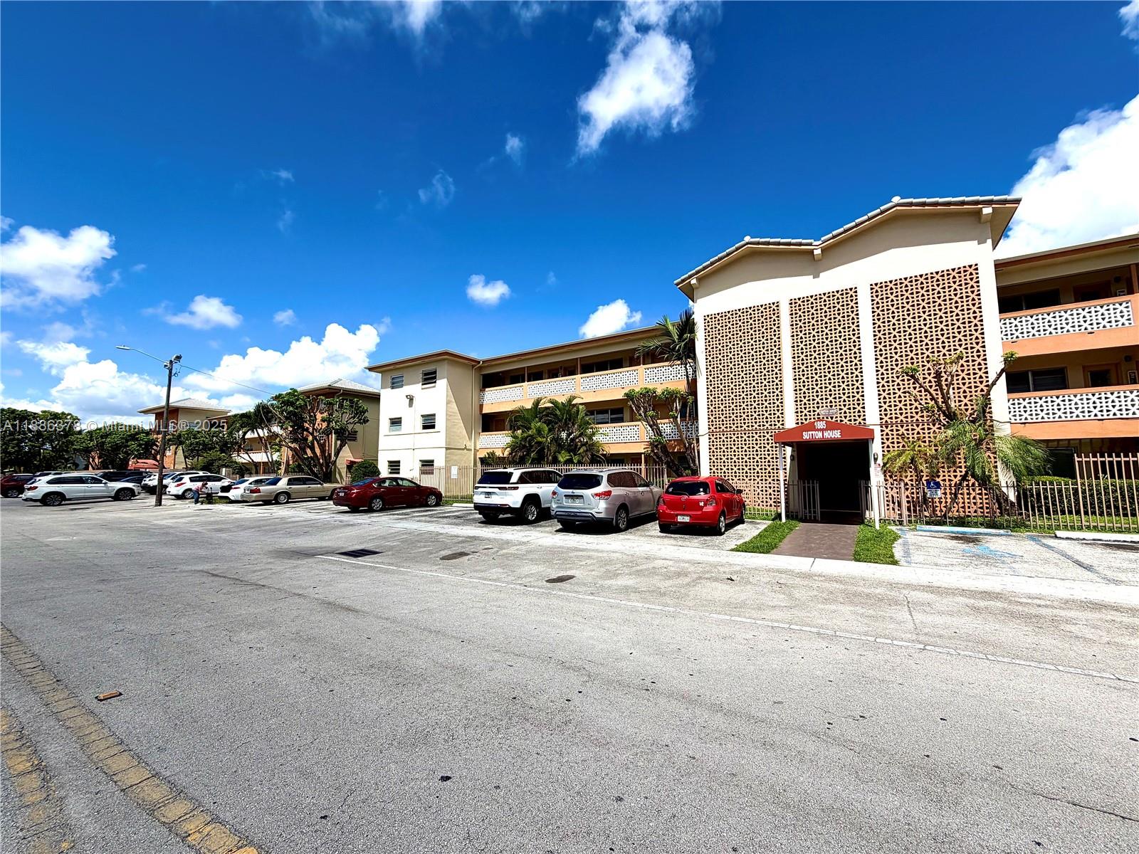 A multi-story apartment building with a parking lot in front under a blue sky — 1885 NE 121st St # 3, North Miami FL 33181, NORTH MIAMI, FL