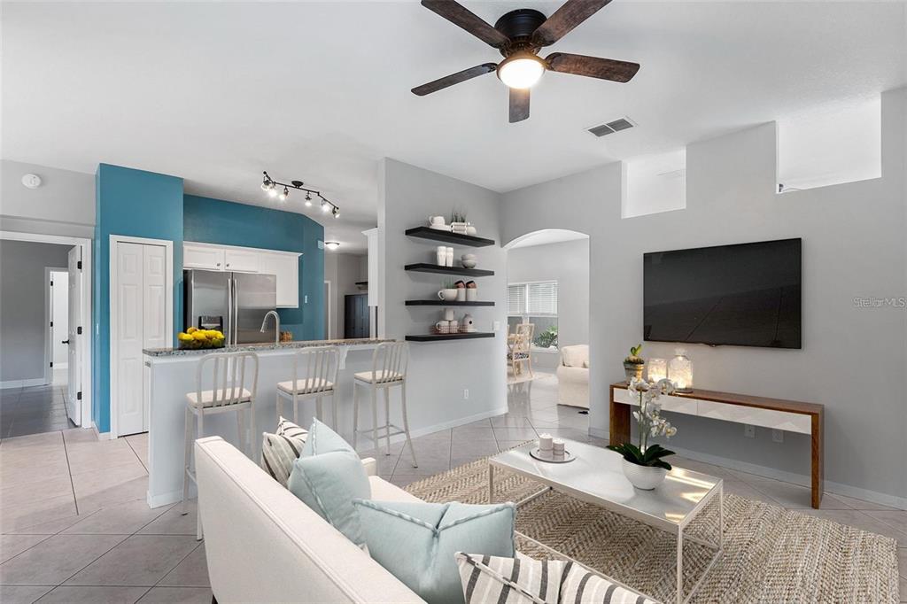 A living room with a kitchen island, floating shelves, and a wall-mounted television — 2997 CEDAR GLEN PLACE, OVIEDO, FL