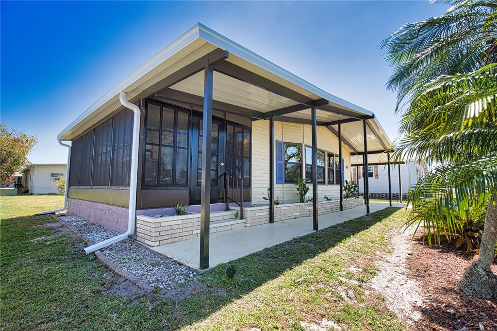 A single-story home with a screened-in porch, a covered patio, and light-colored siding — 407 MADONNA, NORTH PORT, FL