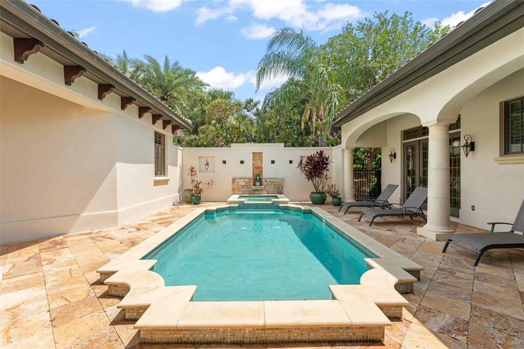 A rectangular swimming pool with a stone deck sits between two wings of a house — 4819 ALEXANDRA GARDEN COURT, WINDERMERE, FL