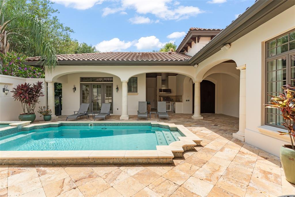 A swimming pool sits on a stone patio in front of a covered outdoor living area — 4819 ALEXANDRA GARDEN COURT, WINDERMERE, FL
