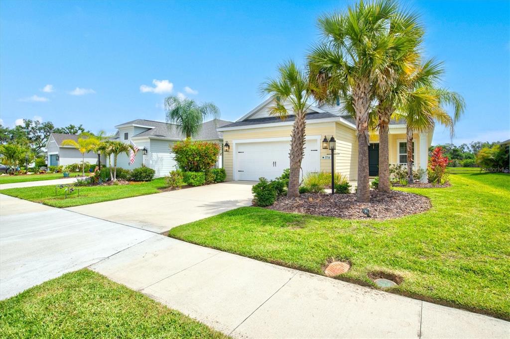 A living room with a tray ceiling, light wood furniture, and sliding doors overlooking a pond — 3714 WOODMONT DRIVE, PARRISH, FL