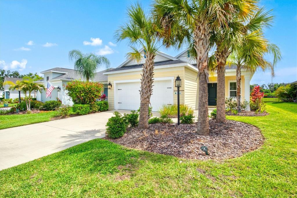 An open-concept living room and kitchen feature light wood furniture, neutral decor, and tile flooring — 3714 WOODMONT DRIVE, PARRISH, FL