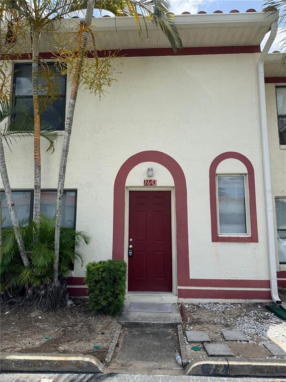 A two-story townhouse exterior features a red front door, arched trim, and palm trees — 1643 SANDY POINT SQUARE UNIT 72, ORLANDO, FL
