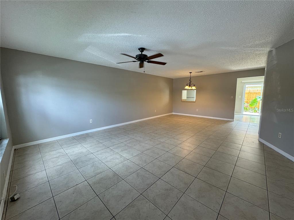 An open-concept living and dining area features light tile flooring and a ceiling fan — 1643 SANDY POINT SQUARE UNIT 72, ORLANDO, FL