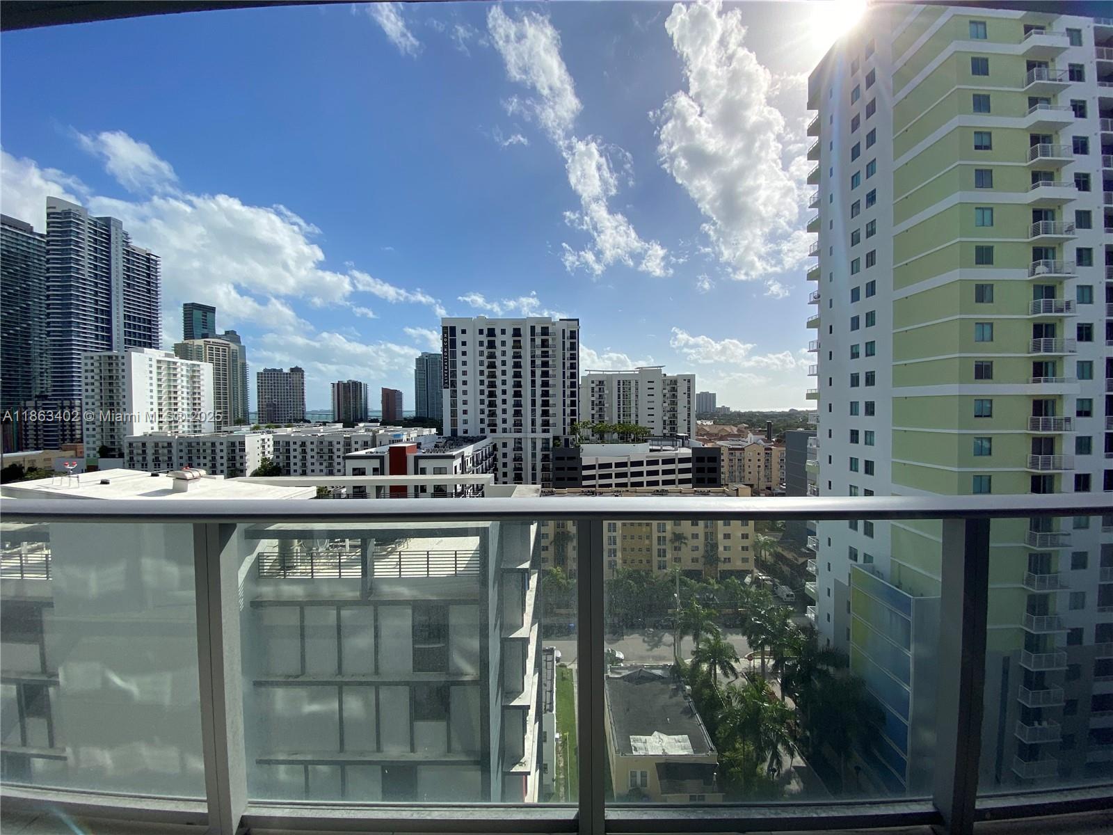 A view from a high-rise balcony overlooking a city skyline with various apartment buildings — 1010 SW 2 AVE # 1110, Miami FL 33130, MIAMI, FL