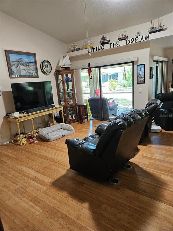 A living room features wood flooring, a television on a console, and nautical-themed decor — 277 ALBATROSS ROAD, ROTONDA WEST, FL