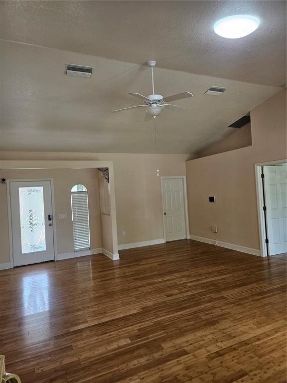 An interior view of a living room with wood flooring, a ceiling fan, and vaulted ceilings — 277 ALBATROSS ROAD, ROTONDA WEST, FL