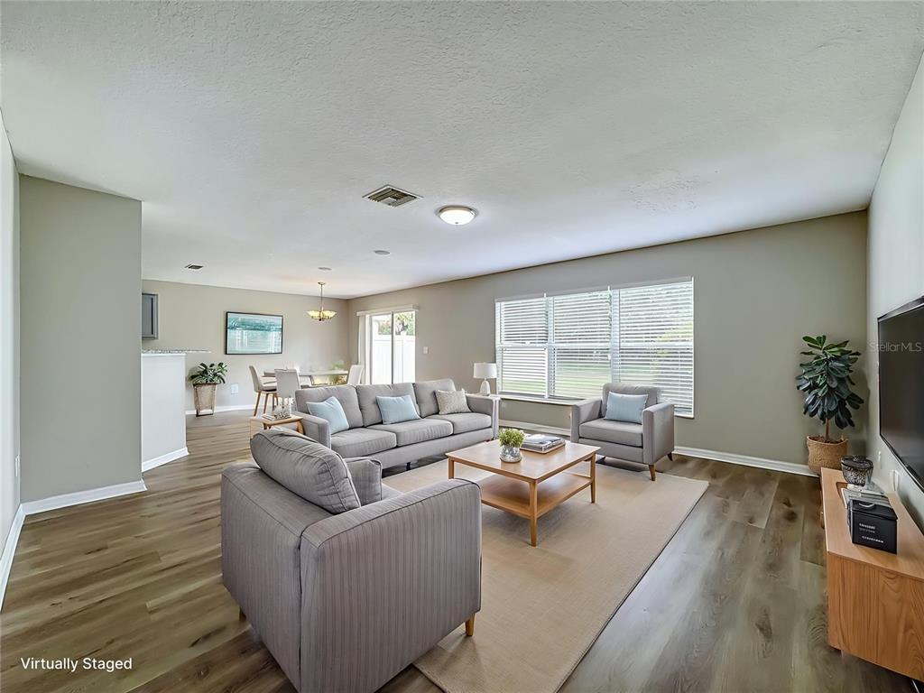 A living room with gray walls, wood-look flooring, and a sofa set on a rug — 6320 MAGNOLIA TRAILS LANE, GIBSONTON, FL