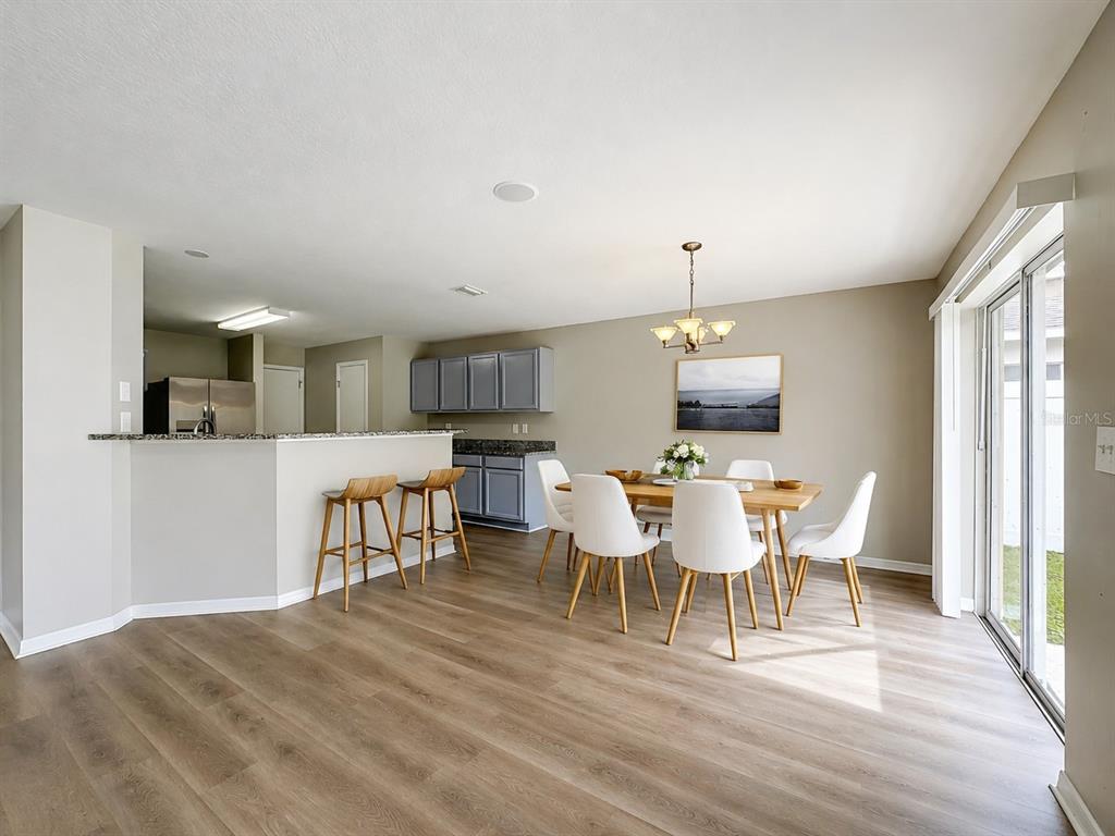 A dining area with a wooden table, white chairs, and a kitchen breakfast bar — 6320 MAGNOLIA TRAILS LANE, GIBSONTON, FL