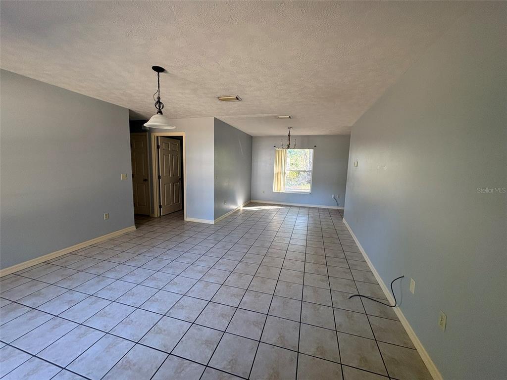 An empty room features light blue walls, a tiled floor, and two hanging light fixtures — 2060 NW 42ND STREET, OCALA, FL