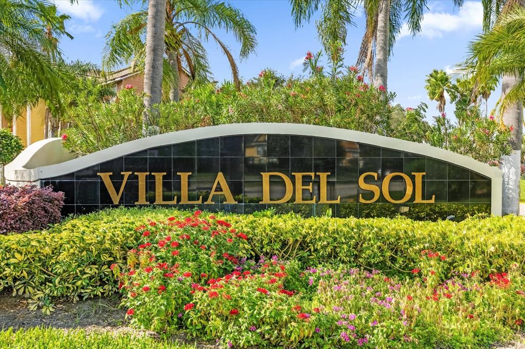 A black stone sign with gold lettering reads Villa Del Sol surrounded by lush landscaping — 2218 GRAND CAYMAN COURT, KISSIMMEE, FL