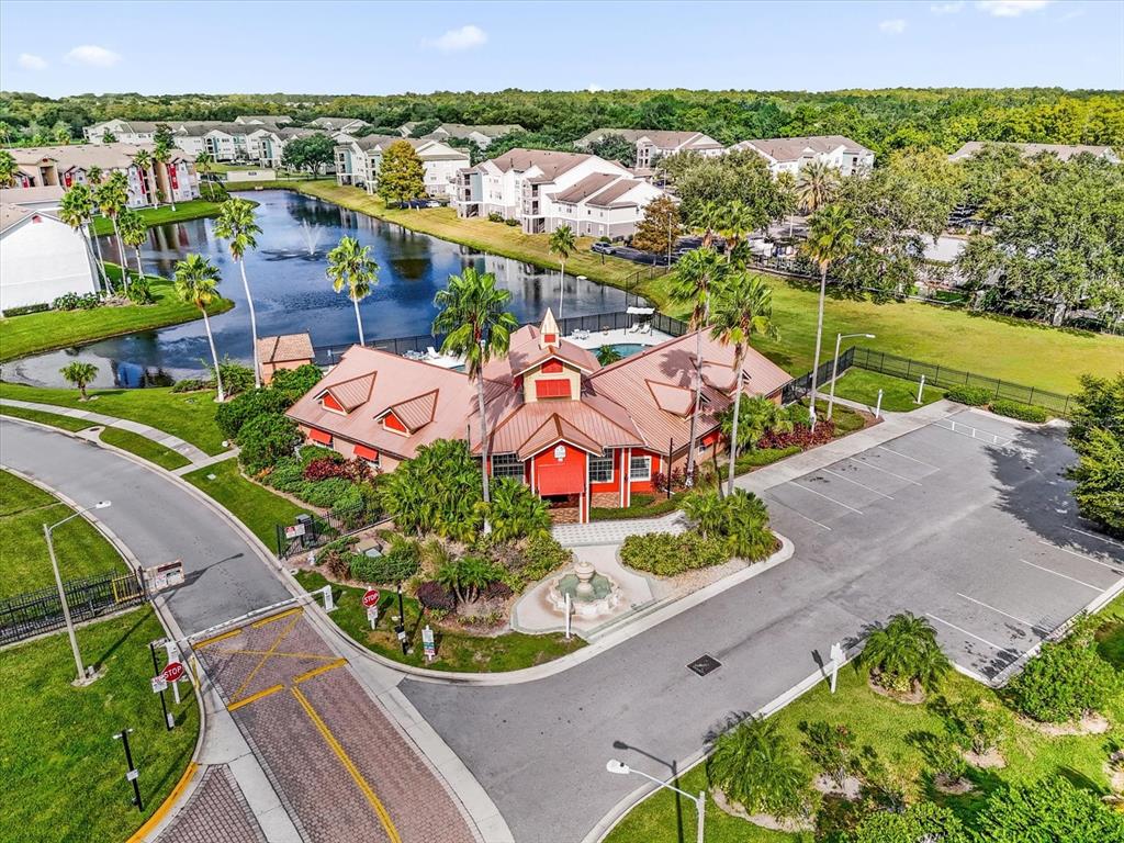 An aerial view shows a community clubhouse with a red roof next to a pond — 2218 GRAND CAYMAN COURT, KISSIMMEE, FL