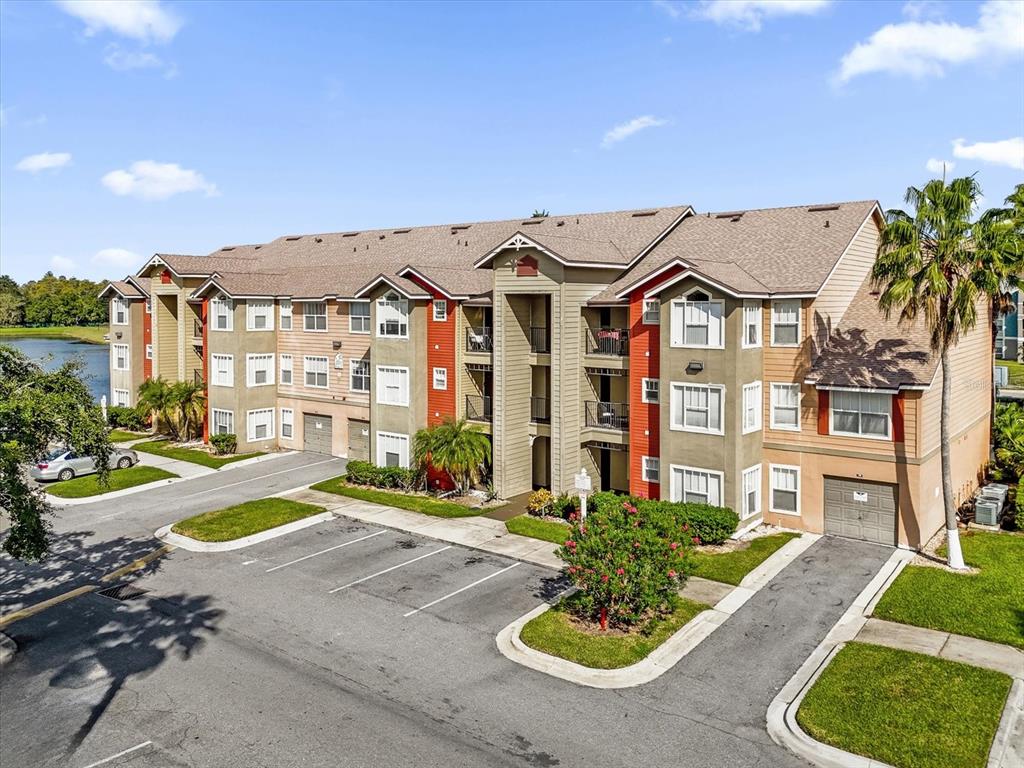 A multi-story apartment building with tan and red siding, a shingled roof, and parking spaces — 2218 GRAND CAYMAN COURT, KISSIMMEE, FL