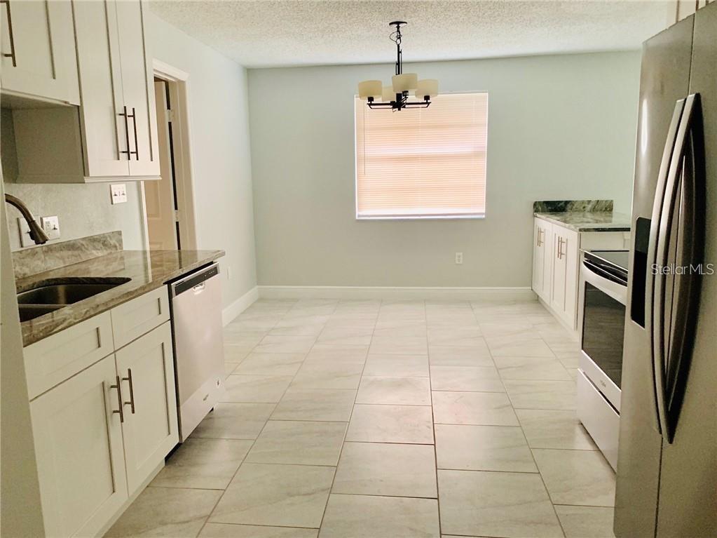 A kitchen with white cabinets, stainless steel appliances, and light-colored tile flooring — 205 BABSON DRIVE, BABSON PARK, FL