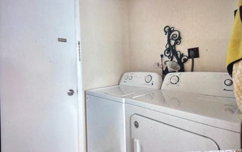 A laundry room features a white washer and dryer next to a closed door — 3224 MOUNT HOPE STREET, NORTH PORT, FL