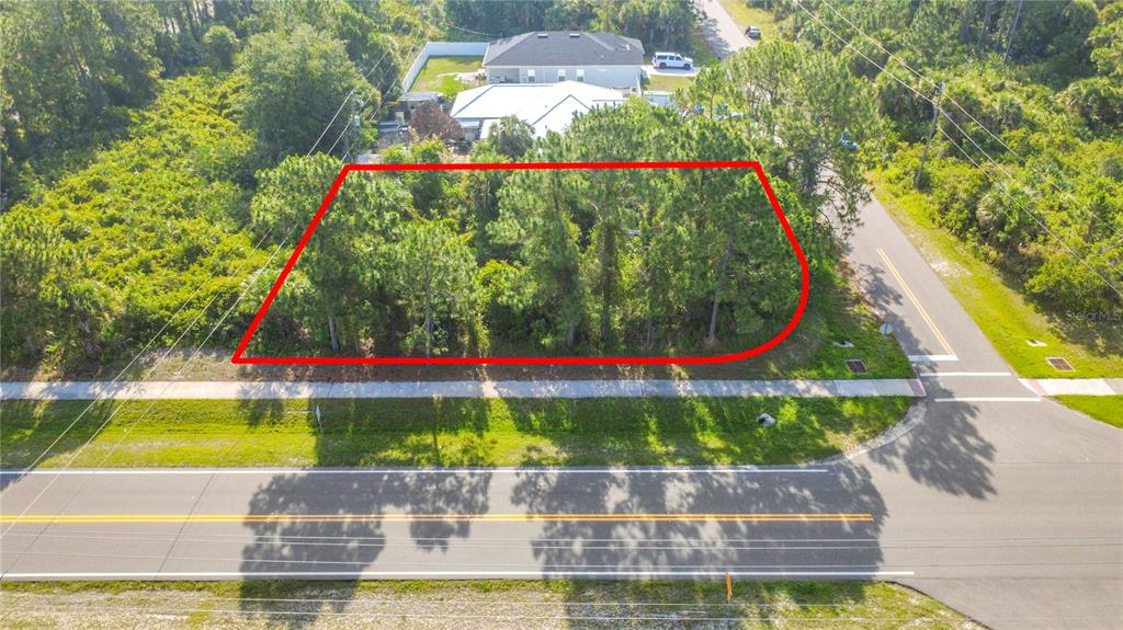 An aerial view shows a rectangular, tree-covered vacant lot bordered by a road and sidewalk — 0 DEGROODT ROAD SW, PALM BAY, FL