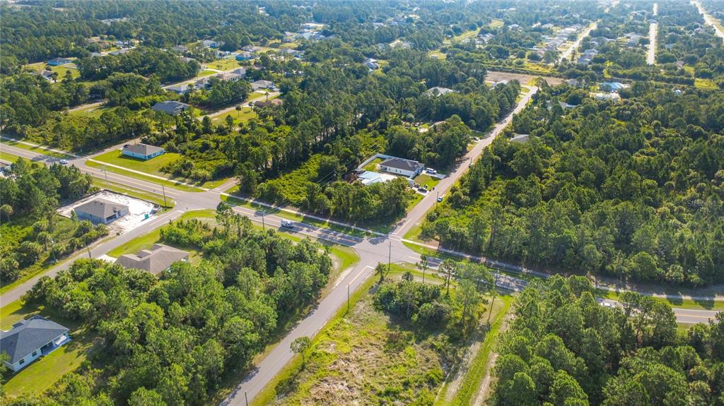 An aerial view shows a residential intersection surrounded by dense woods and scattered single-family homes — 0 DEGROODT ROAD SW, PALM BAY, FL