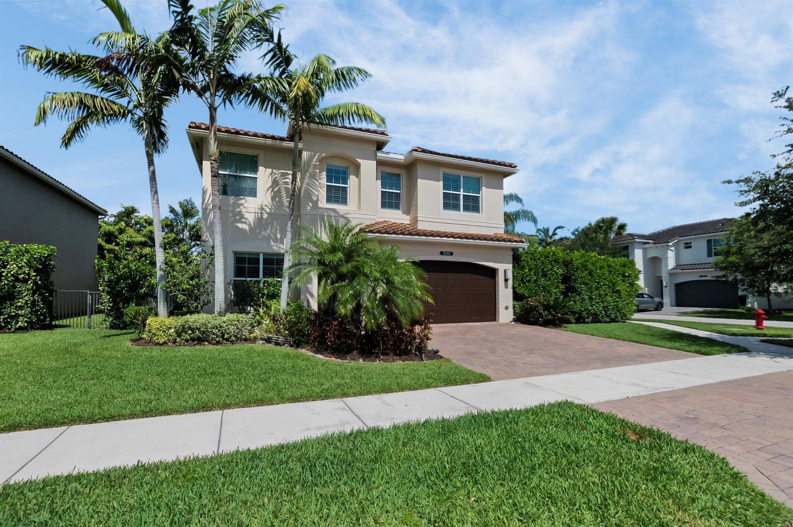A two-story beige house with a brown garage door and palm trees in the front yard — 15205 Seaglass Terrace Lane, Delray Beach FL 33446, DELRAY BEACH, FL