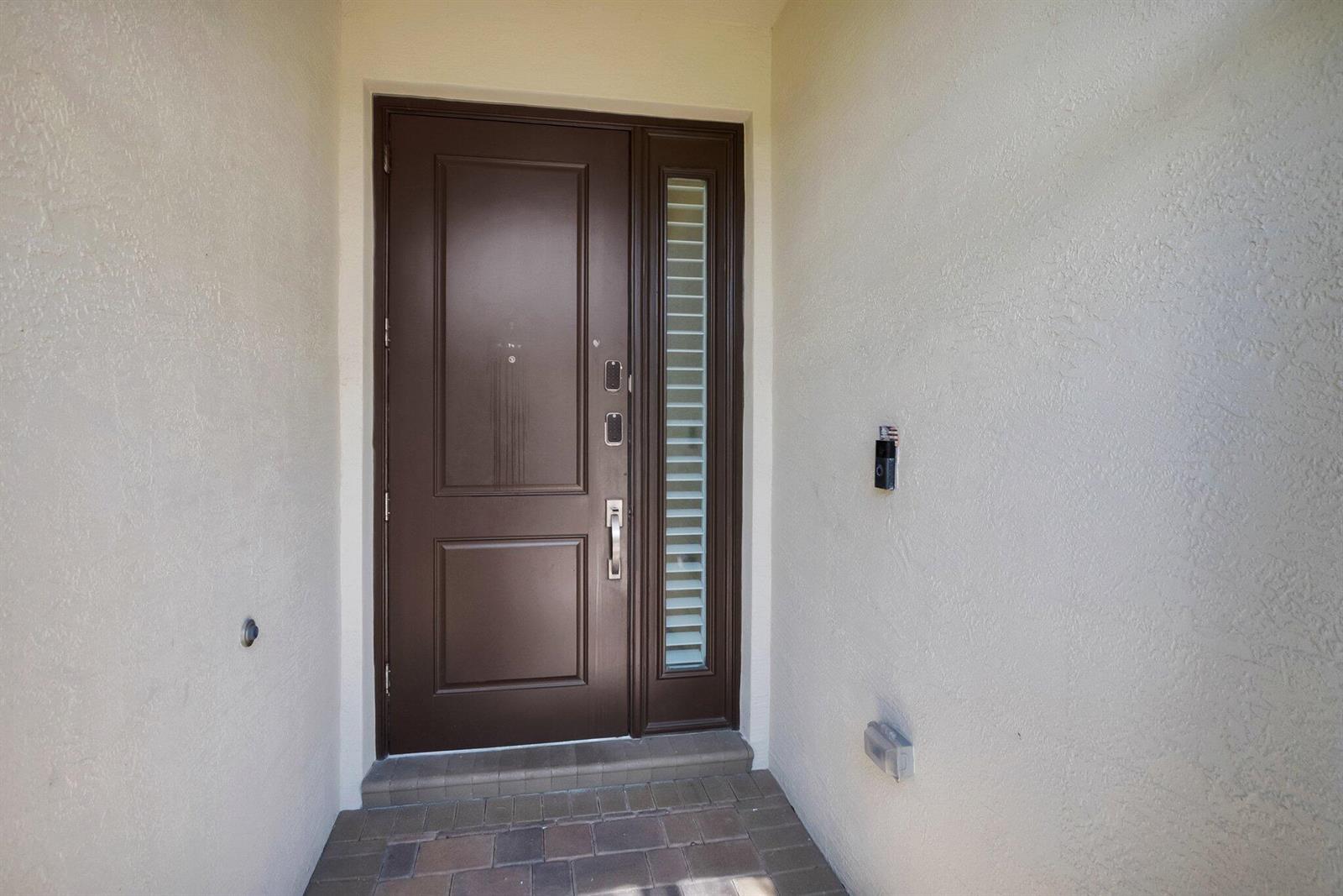 A dark brown front door with a side window sits in a stucco entryway — 15205 Seaglass Terrace Lane, Delray Beach FL 33446, DELRAY BEACH, FL