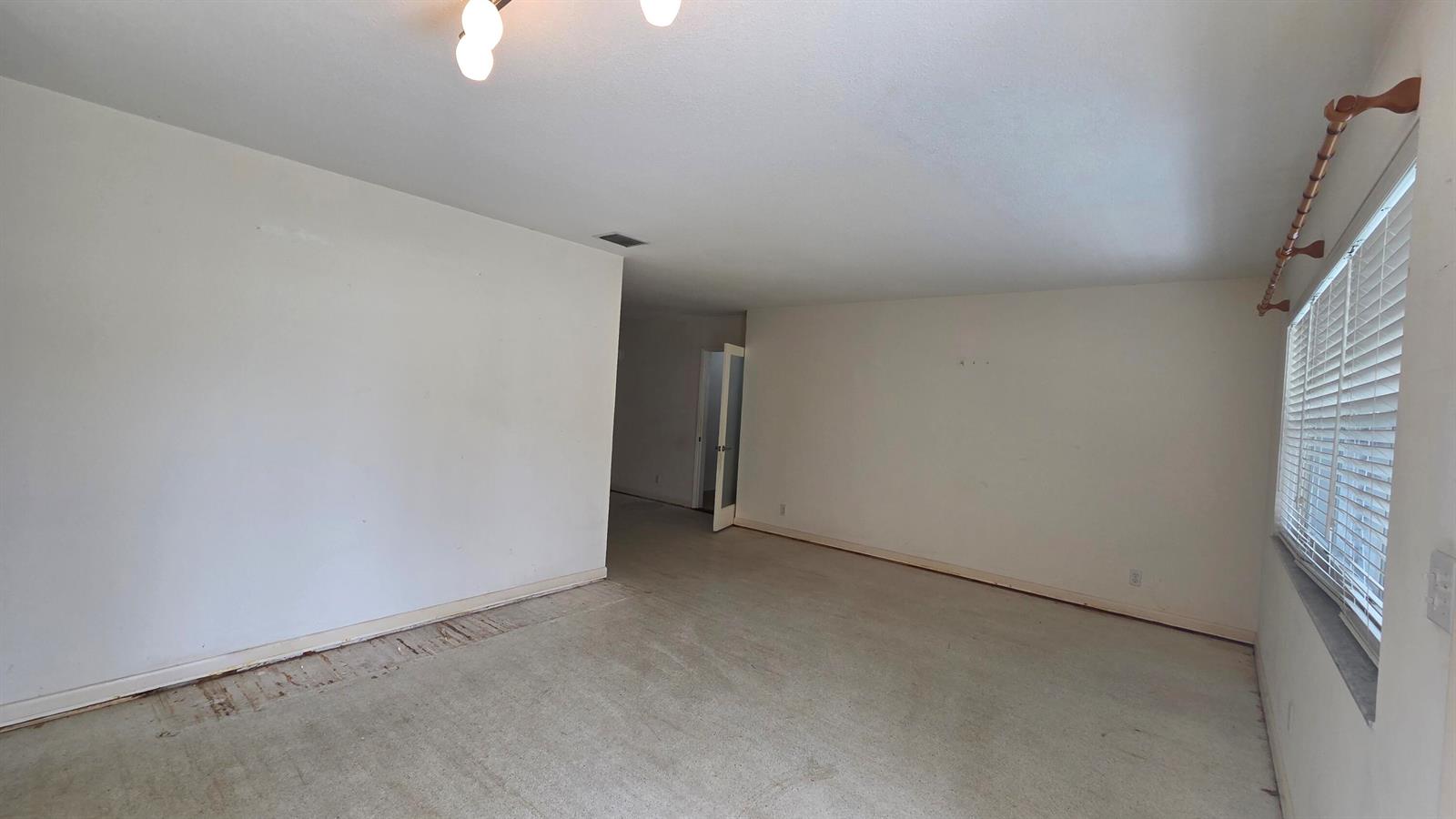 An empty room features white walls, a window with blinds, and worn carpeting — 2000 N 31st Avenue, Hollywood FL 33021, HOLLYWOOD, FL