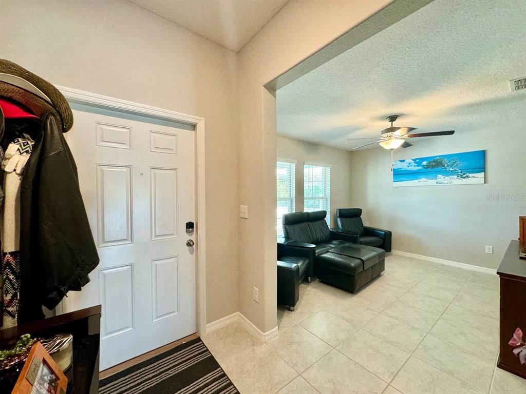 An entryway with a white door leads into a living room with tiled floors — 1881 SAND DAISY PLACE, RUSKIN, FL
