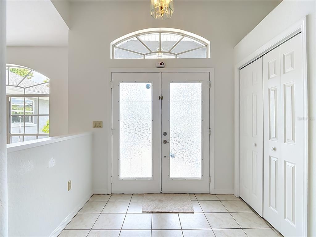 An entryway features white double doors with frosted glass, a tiled floor, and a closet — 13827 WOODWARD DRIVE, HUDSON, FL