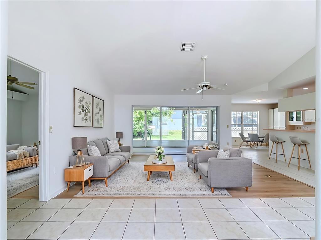 A living room with gray furniture, a wood coffee table, and tile and wood flooring — 13827 WOODWARD DRIVE, HUDSON, FL