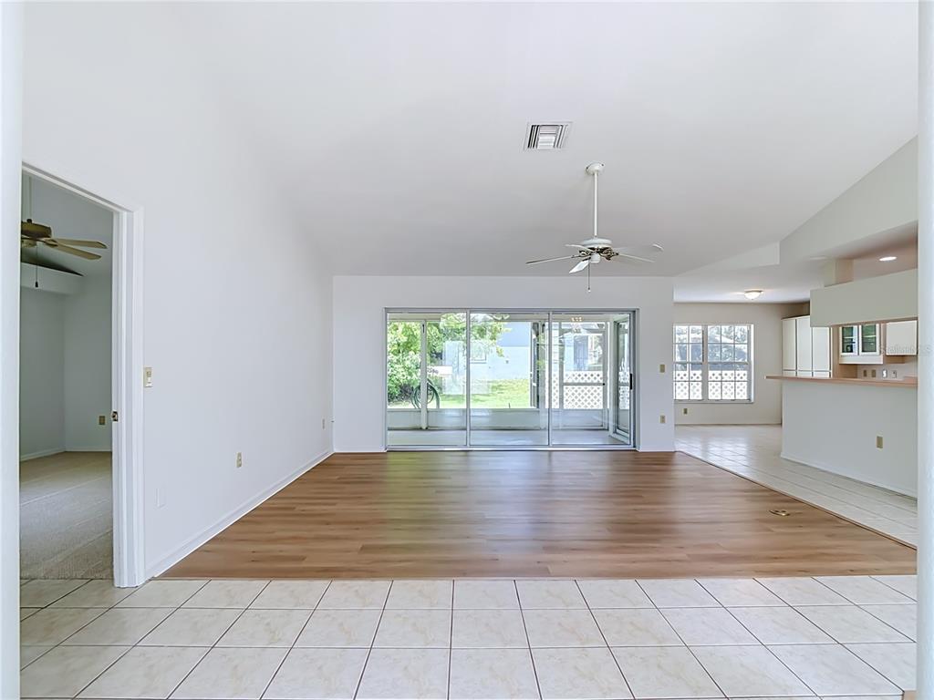 A living room features wood-look flooring, white walls, a ceiling fan, and sliding glass doors — 13827 WOODWARD DRIVE, HUDSON, FL