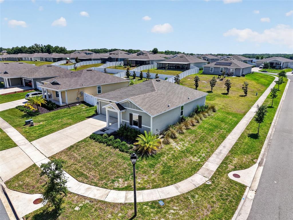 An aerial view shows a suburban neighborhood with single-family homes, lawns, and sidewalks — 5354 TRAVERTINE STREET, MOUNT DORA, FL