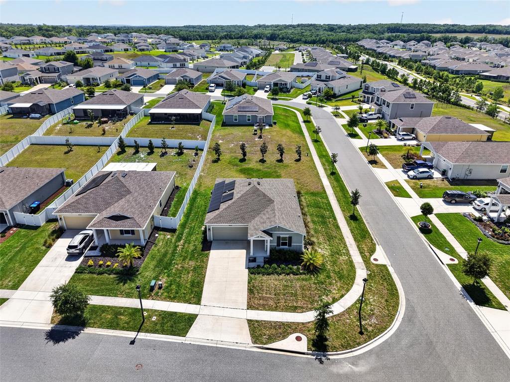 An aerial view shows a suburban neighborhood with single-family homes, paved streets, and green lawns — 5354 TRAVERTINE STREET, MOUNT DORA, FL