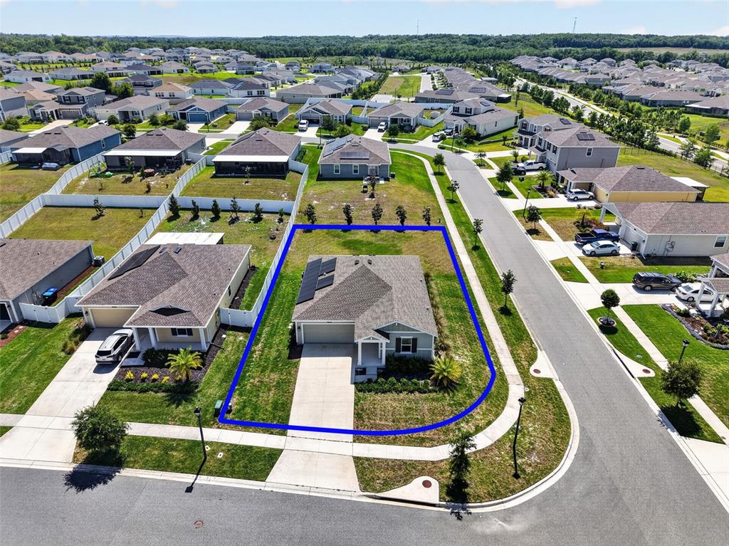 An aerial view shows a single-story house with a solar panel array on the roof — 5354 TRAVERTINE STREET, MOUNT DORA, FL