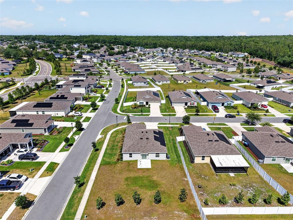 An aerial view shows a suburban neighborhood with single-family homes, paved streets, and green lawns — 5354 TRAVERTINE STREET, MOUNT DORA, FL